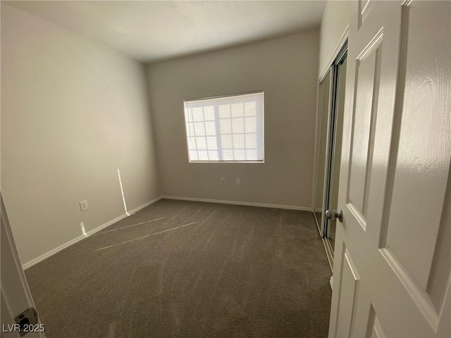 unfurnished bedroom featuring a closet, dark carpet, and baseboards