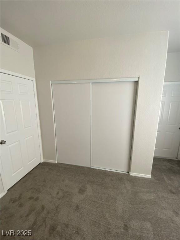 unfurnished bedroom with a closet, carpet, and visible vents