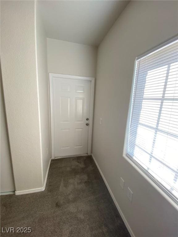 doorway to outside featuring dark carpet and baseboards