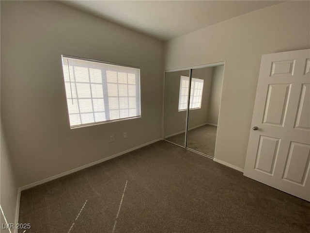 unfurnished bedroom featuring a closet, dark carpet, and baseboards