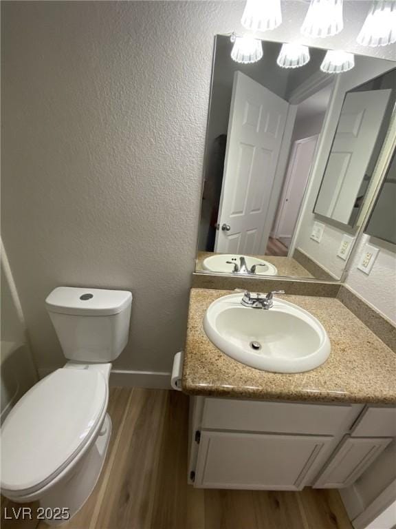 bathroom featuring a textured wall, vanity, toilet, and wood finished floors