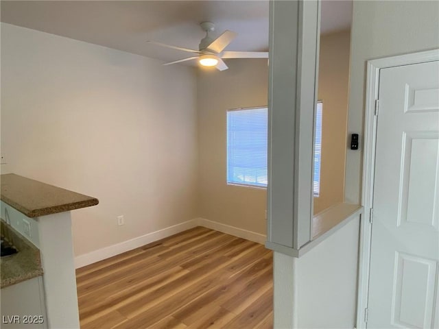 interior space featuring light wood-type flooring, ceiling fan, and baseboards