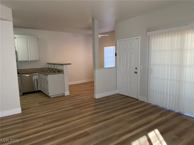 kitchen with a peninsula, stainless steel dishwasher, wood finished floors, and white cabinets