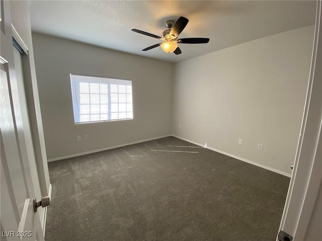 unfurnished room with baseboards, dark carpet, and a ceiling fan