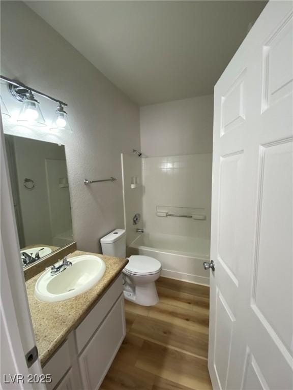 bathroom with toilet, shower / washtub combination, wood finished floors, and vanity