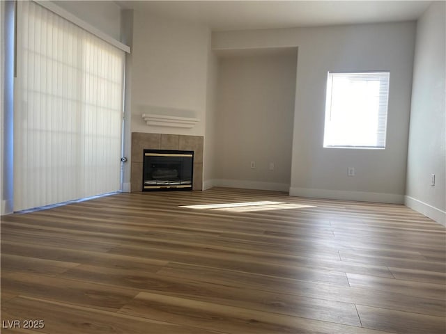 unfurnished living room with a fireplace, wood finished floors, and baseboards