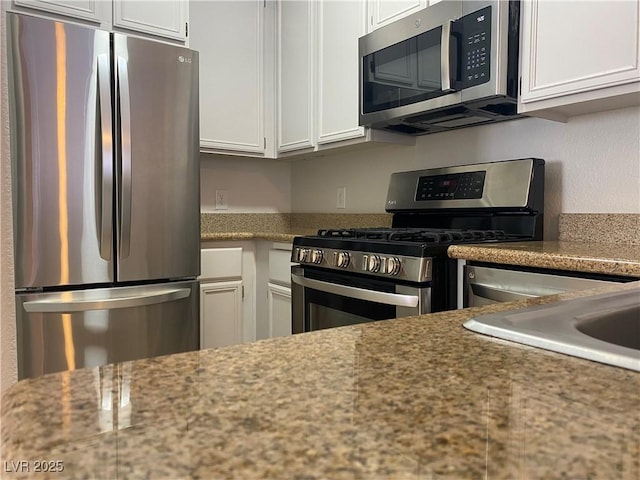 kitchen with stainless steel appliances, a sink, and white cabinets