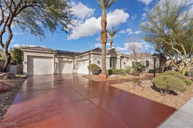 view of front facade featuring stucco siding, an attached garage, roof mounted solar panels, driveway, and a tiled roof