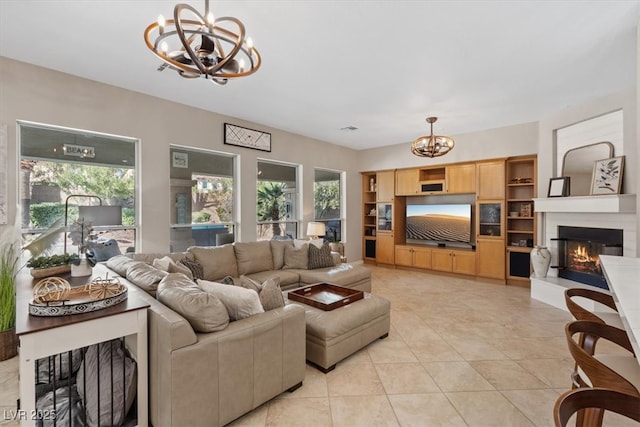 living room with light tile patterned floors, a glass covered fireplace, and a notable chandelier