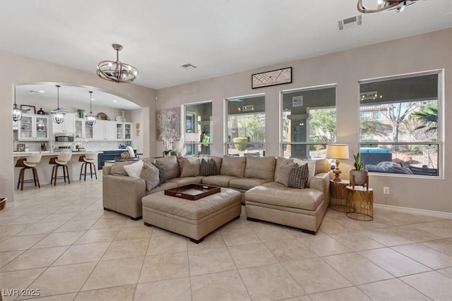 living room featuring light tile patterned floors, a healthy amount of sunlight, visible vents, and an inviting chandelier