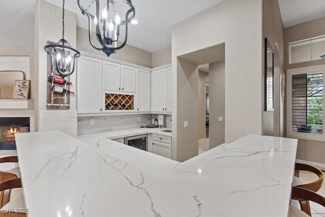 kitchen featuring tasteful backsplash, light stone counters, a kitchen breakfast bar, and a notable chandelier