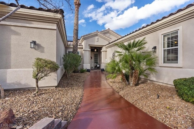 entrance to property featuring a tile roof and stucco siding