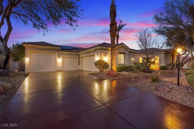 view of front facade with solar panels, concrete driveway, a tile roof, an attached garage, and stucco siding