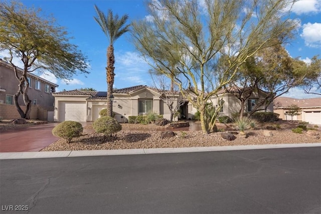 view of front of home with an attached garage, a tile roof, concrete driveway, roof mounted solar panels, and stucco siding