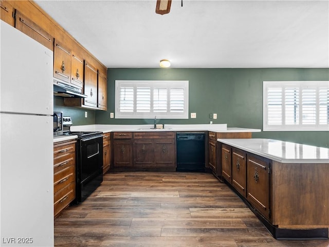 kitchen featuring a peninsula, black appliances, light countertops, and a sink