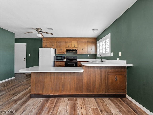 kitchen featuring visible vents, a peninsula, electric range, freestanding refrigerator, and light countertops