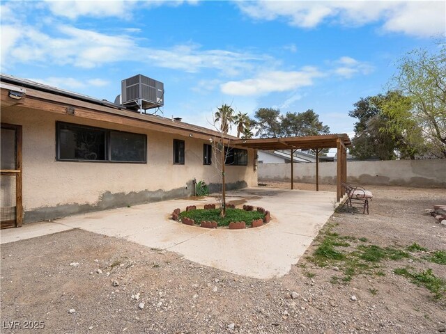 back of property with a carport, central air condition unit, fence, and stucco siding