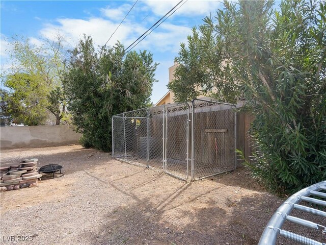 view of outbuilding with fence and an outdoor fire pit