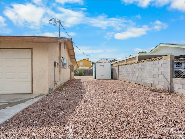 exterior space featuring stucco siding, a storage shed, an outdoor structure, and fence