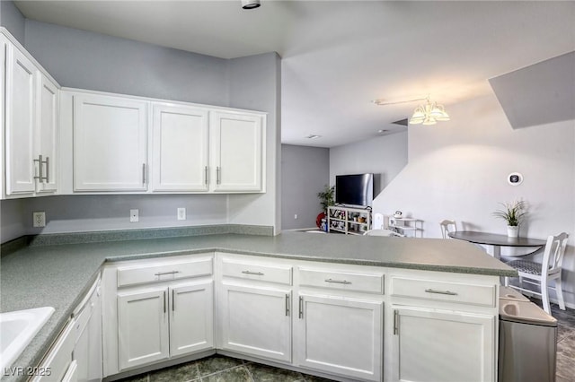 kitchen featuring a peninsula, white cabinetry, and a sink