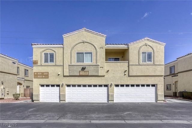 view of front facade featuring an attached garage, cooling unit, a tile roof, and stucco siding