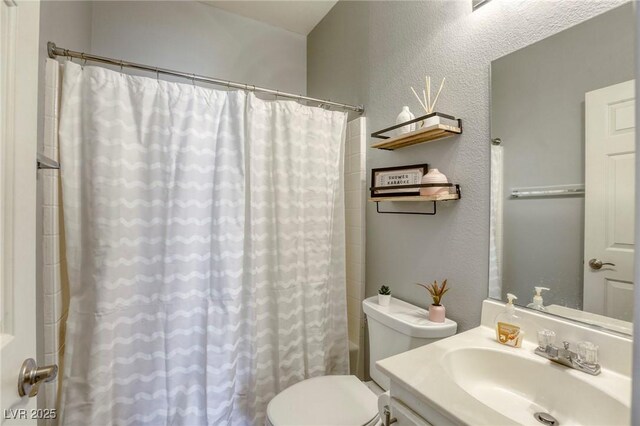 bathroom featuring a textured wall, vanity, and toilet