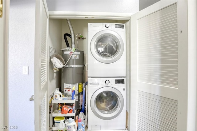 clothes washing area featuring stacked washer / drying machine, laundry area, and strapped water heater