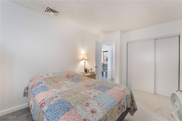 carpeted bedroom featuring a closet, visible vents, and a textured ceiling