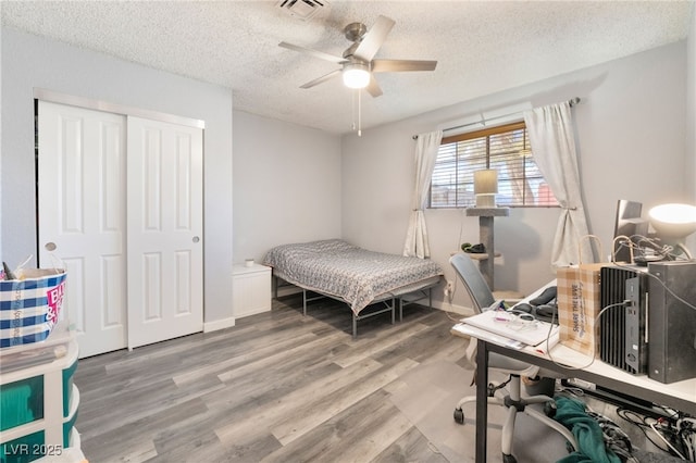 bedroom featuring visible vents, a ceiling fan, wood finished floors, a textured ceiling, and a closet