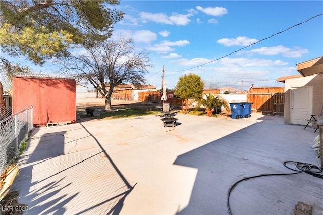 view of patio / terrace with an outdoor fire pit, a fenced backyard, an outbuilding, and a shed