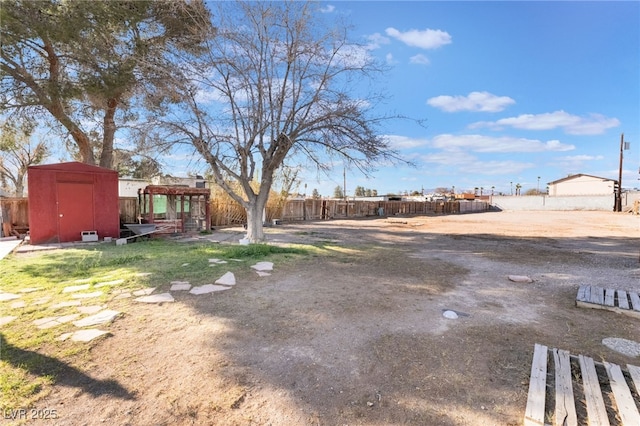 view of yard featuring an outbuilding, a storage shed, and fence