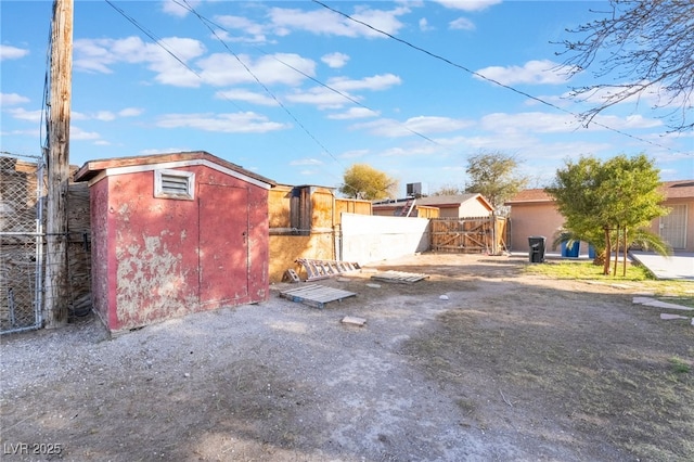 exterior space with a shed, an outdoor structure, fence, and stucco siding