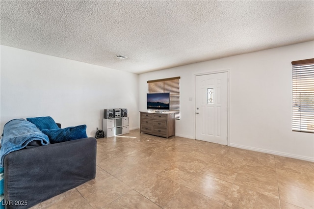 living room featuring baseboards, visible vents, and a textured ceiling