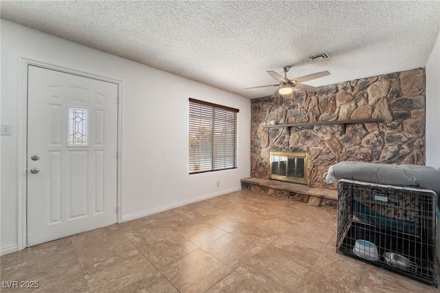 living room with baseboards, visible vents, ceiling fan, a textured ceiling, and a fireplace