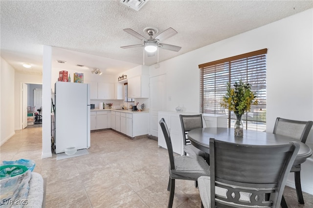 dining room with a ceiling fan, visible vents, and a textured ceiling