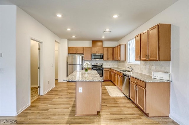 kitchen with stainless steel appliances, a kitchen island, a sink, visible vents, and light wood-type flooring