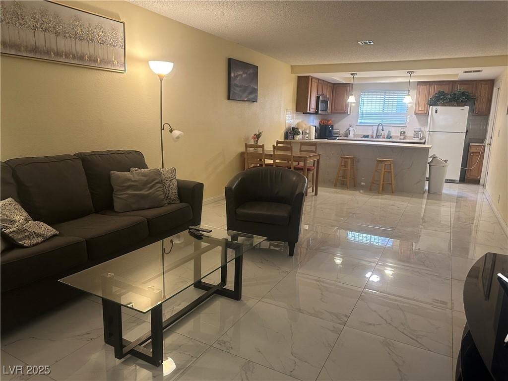 living area featuring marble finish floor, baseboards, and a textured ceiling