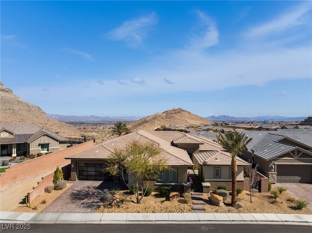 view of front facade featuring a garage, decorative driveway, a residential view, and a mountain view