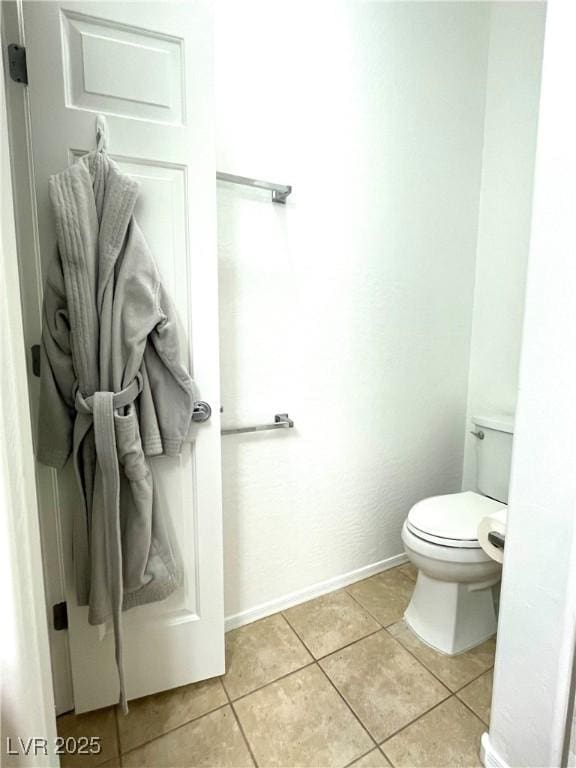 bathroom with baseboards, toilet, and tile patterned flooring