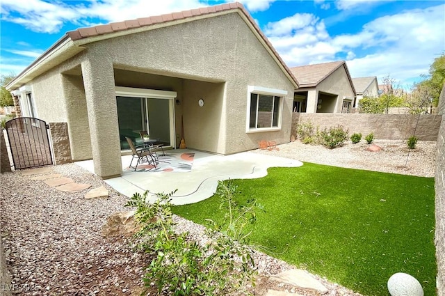 rear view of property featuring fence, a tiled roof, stucco siding, a patio area, and a gate