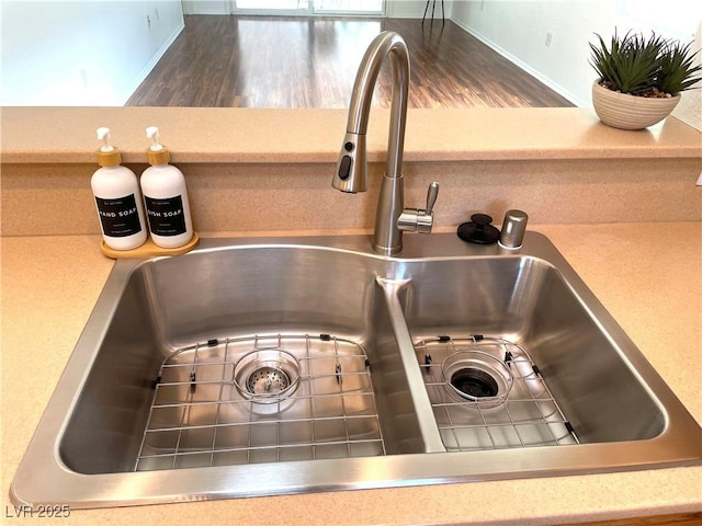 room details with a sink, wood finished floors, and light countertops