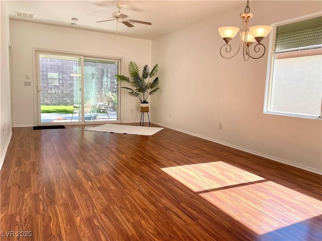 spare room featuring visible vents, ceiling fan with notable chandelier, baseboards, and wood finished floors