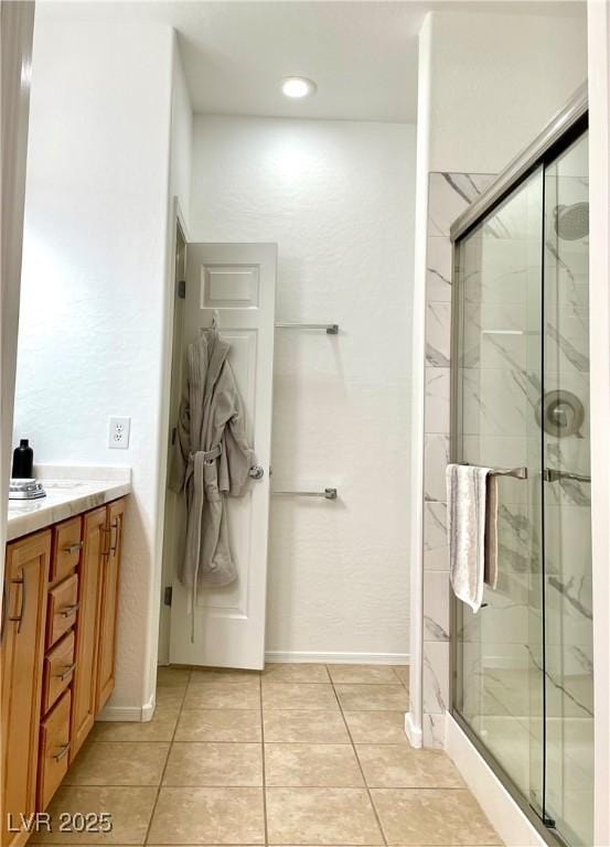 full bath with a marble finish shower, tile patterned floors, and baseboards