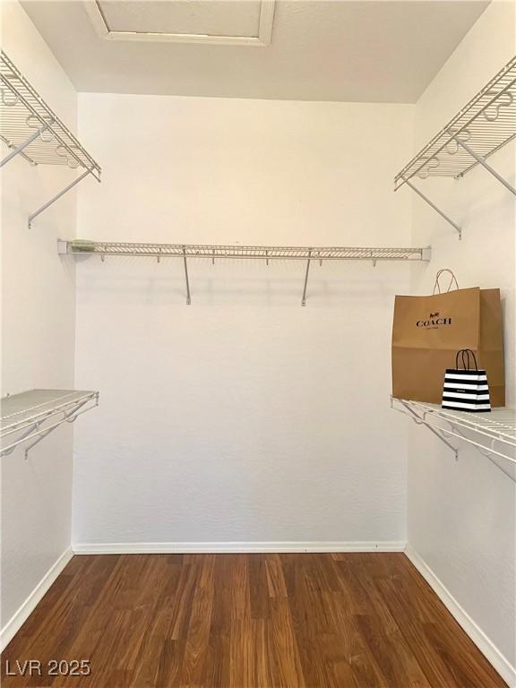 walk in closet featuring attic access and wood finished floors