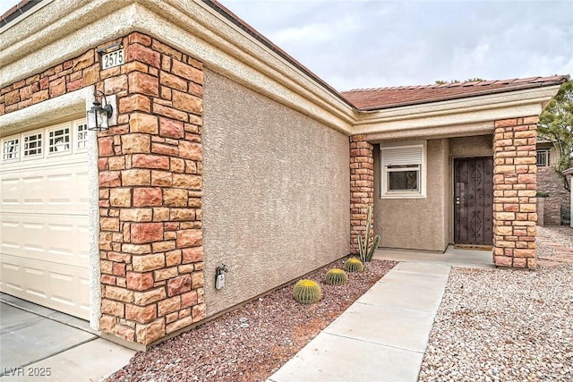 entrance to property with a tiled roof, a garage, and stucco siding