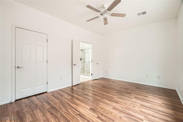 unfurnished bedroom featuring wood finished floors, visible vents, ensuite bathroom, and baseboards