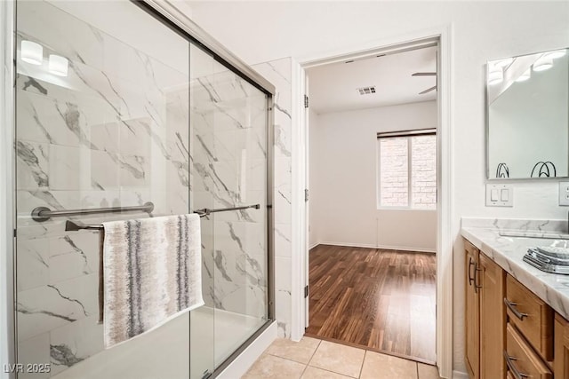 bathroom with a marble finish shower, visible vents, tile patterned floors, and vanity