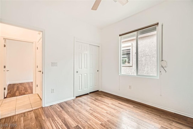 unfurnished bedroom with a closet, baseboards, ceiling fan, and light wood finished floors