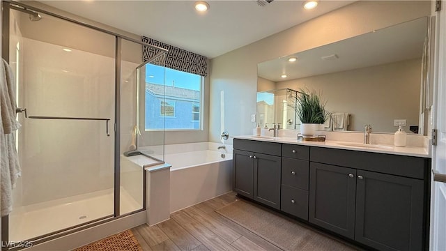 4181 Nopal Serrano Ave, Las Vegas, NV 89141 - bathroom featuring a bath, double vanity, wood finished floors, a shower stall, and recessed lighting