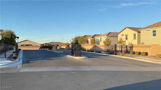 view of road with a residential view, sidewalks, curbs, and a gated entry